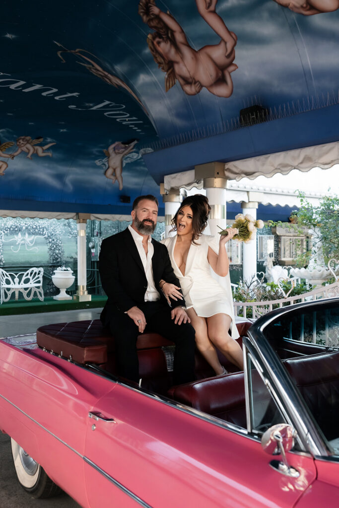 Bride and groom sitting in the iconic pink Cadillac inside the Tunnel of Love at The Little White Wedding Chapel.