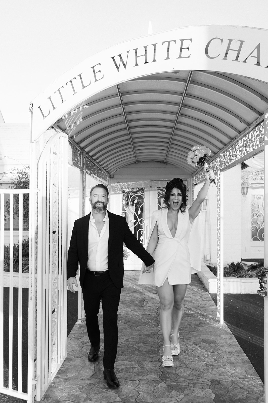 Bride and groom celebrating and walking out of The Little White Wedding Chapel after their elopement ceremony.