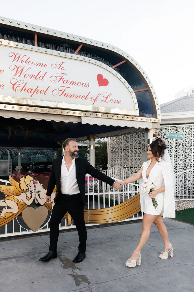Bride and groom holding hands outside the Tunnel of Love entrance at The Little White Wedding Chapel in Las Vegas.