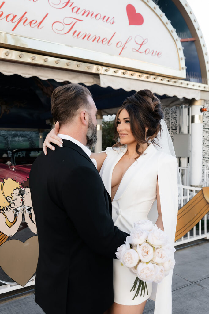 Bride and groom posing outside the Tunnel of Love entrance at The Little White Wedding Chapel in Las Vegas.