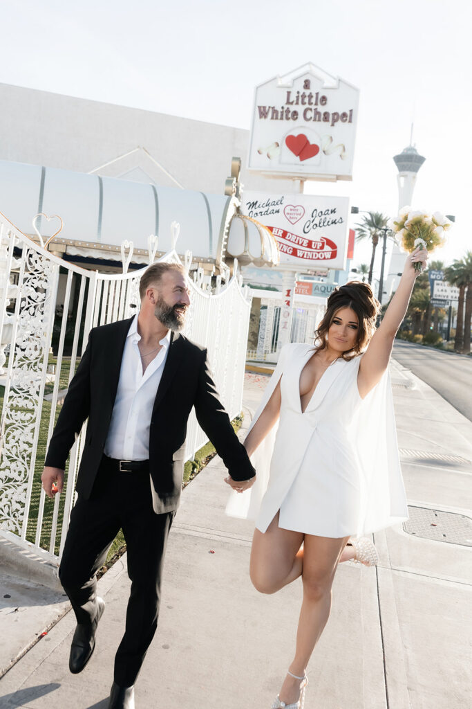 Bride and groom walking down the sidewalk outside of The Little White Wedding Chapel in Las Vegas.