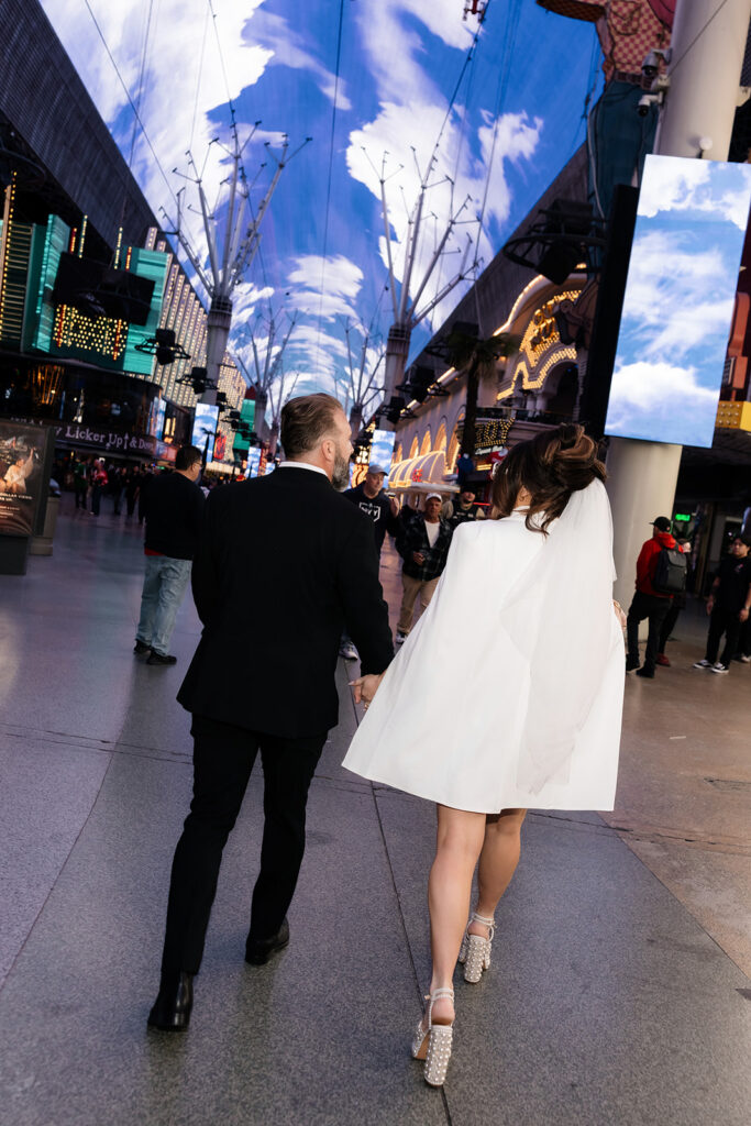 Bride and groom walking down Fremont Street together. 