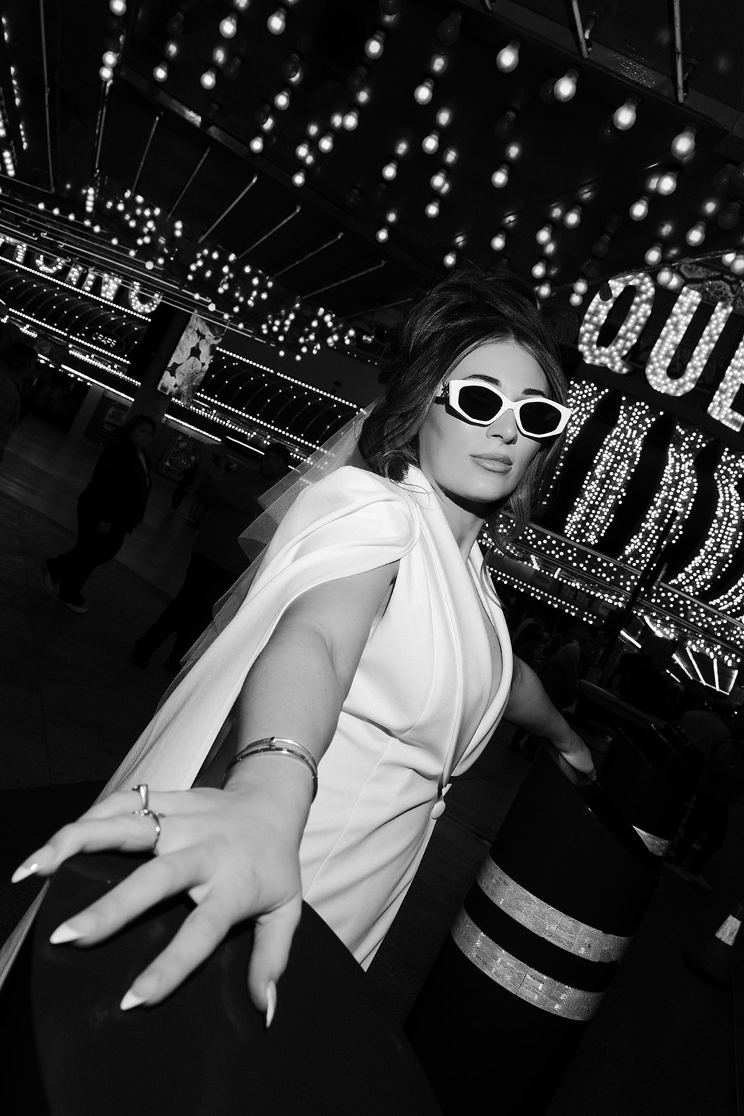 Bride posing with sunglasses under the neon lights of Fremont Street in downtown Las Vegas.