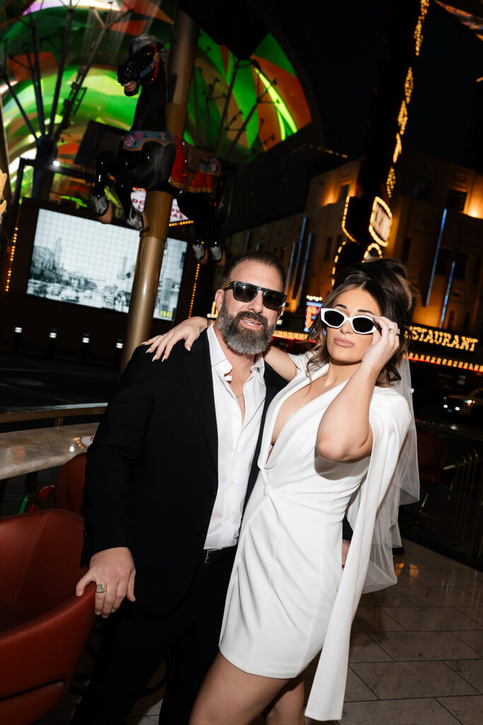 Bride and groom wearing sunglasses and posing at Carousel Bar on Fremont Street for their elopement photos. 