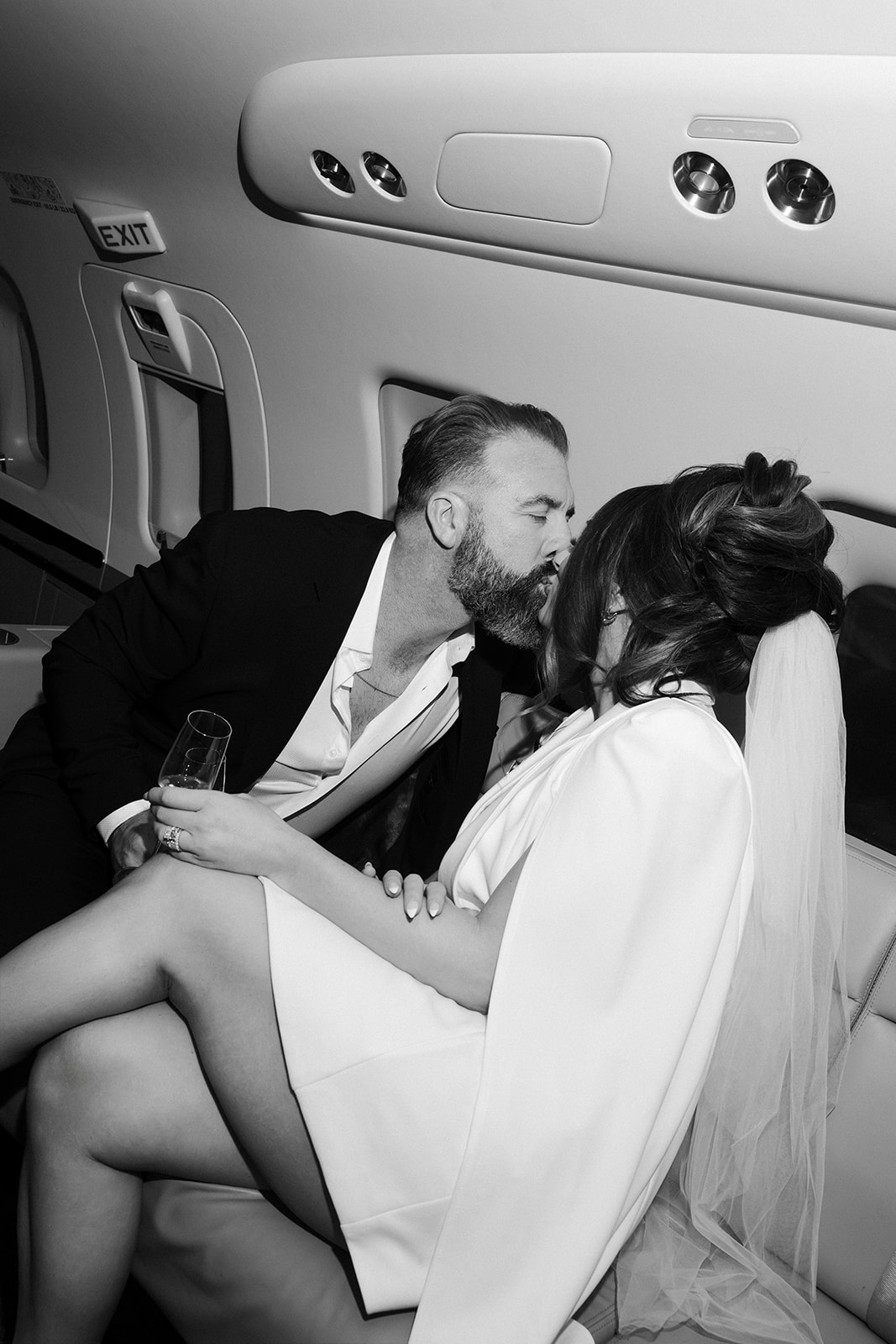 Bride and groom kissing with champagne inside a private jet during their Las Vegas luxury elopement.