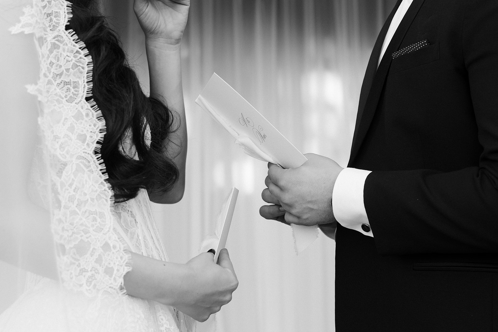 Black and white close up shot of a bride and groom reading their vows during the ceremony.