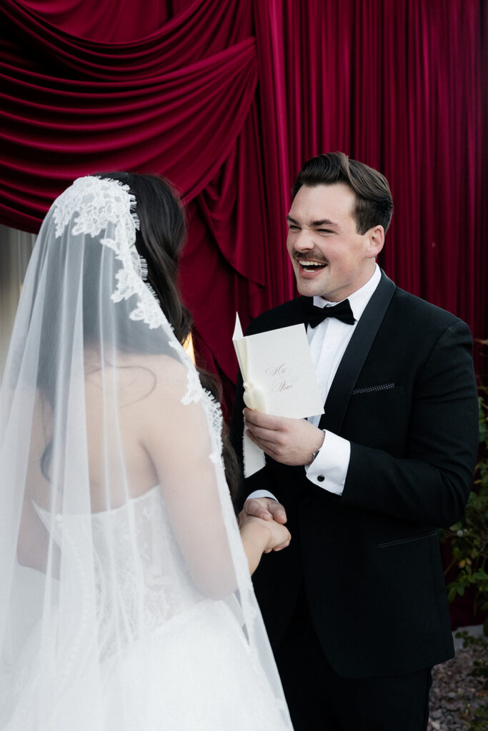 Groom laughing while he reads his bride his vows during a Lotus House wedding ceremony in Las Vegas.