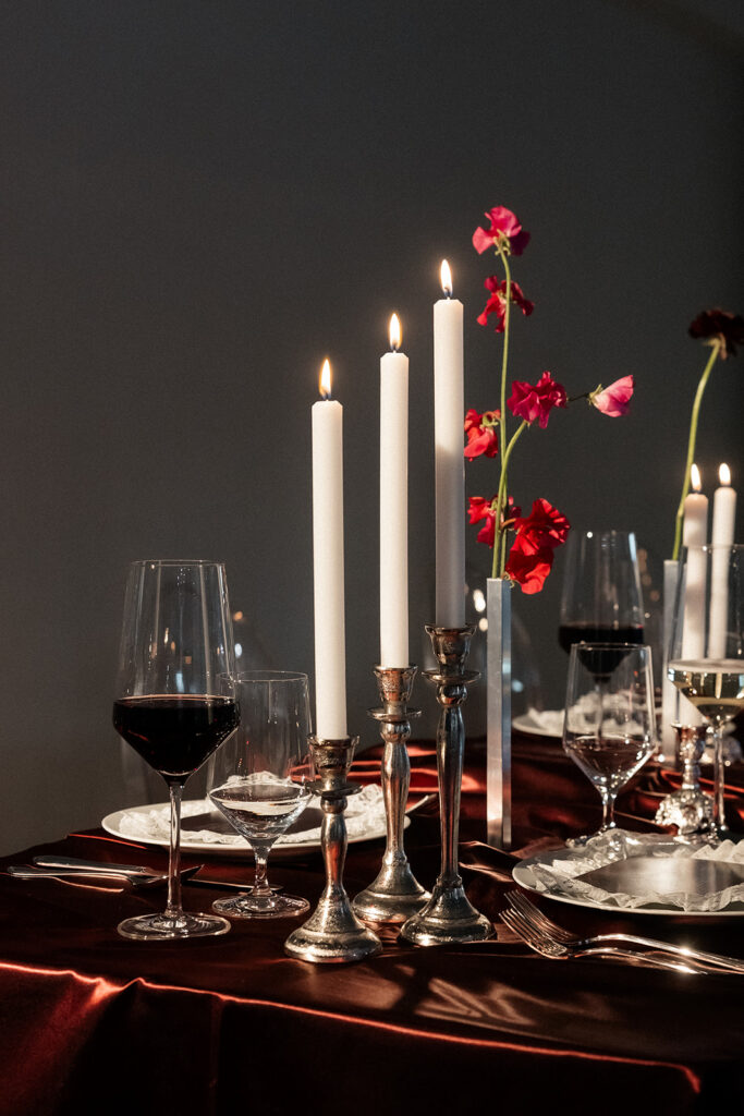 Elegant candlelit reception table with red florals and glassware at The Lotus House wedding venue in Las Vegas.
