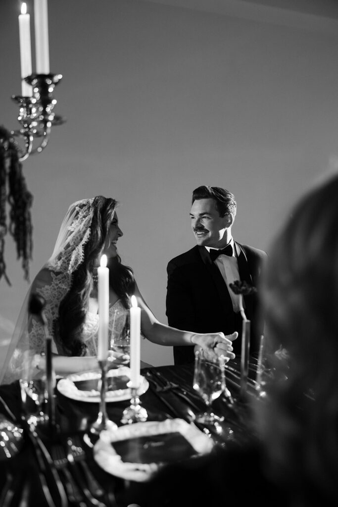 Bride and groom holding hands at candlelit reception table at The Lotus House wedding venue in Las Vegas.