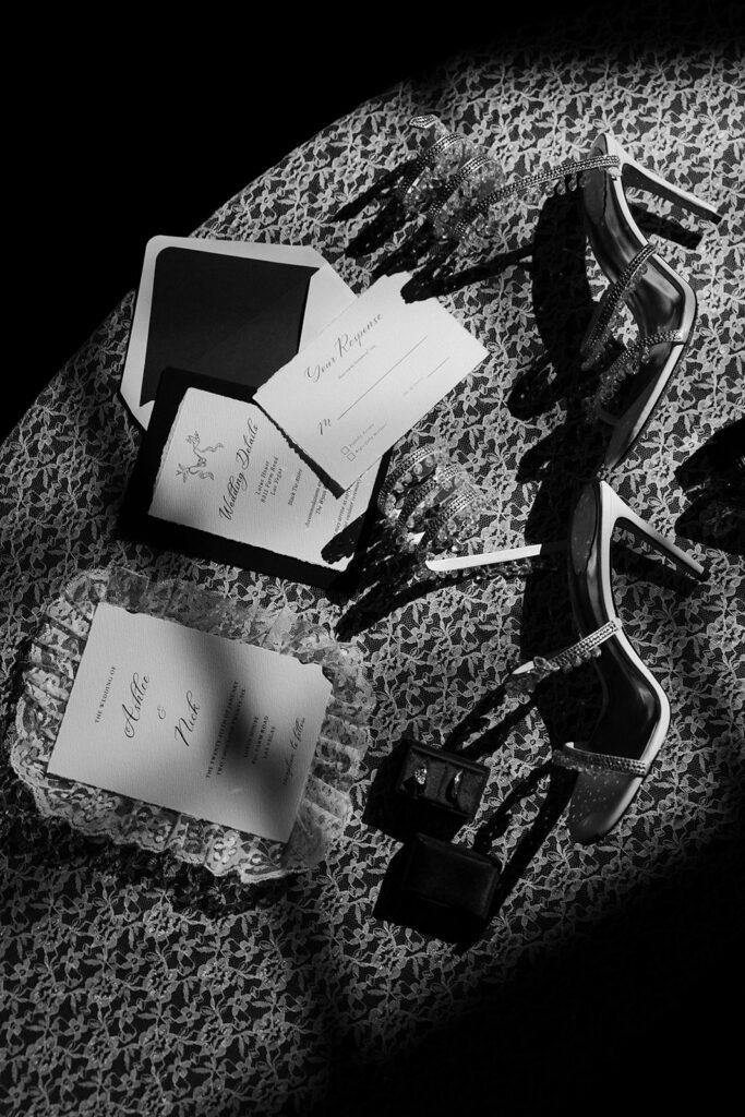 Wedding details flat lay with invitation suite, heels, and rings at The Lotus House wedding venue in Las Vegas.