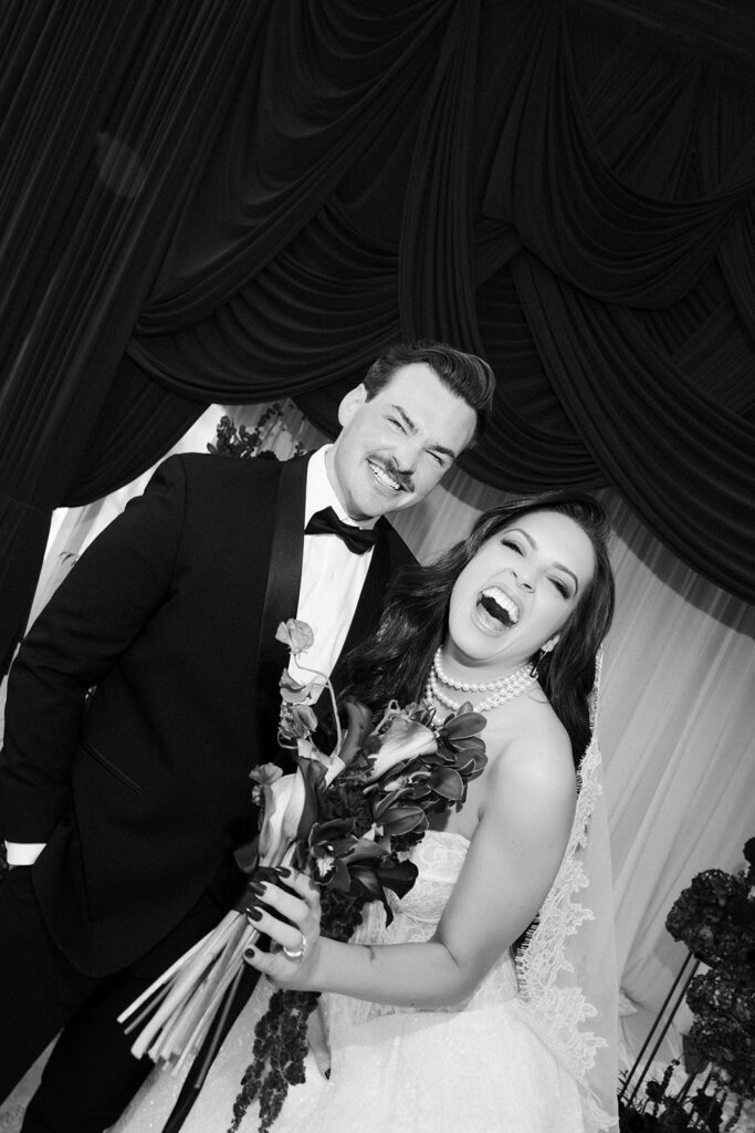 Black and white candid shot of a bride and groom laughing captured with flash photography.