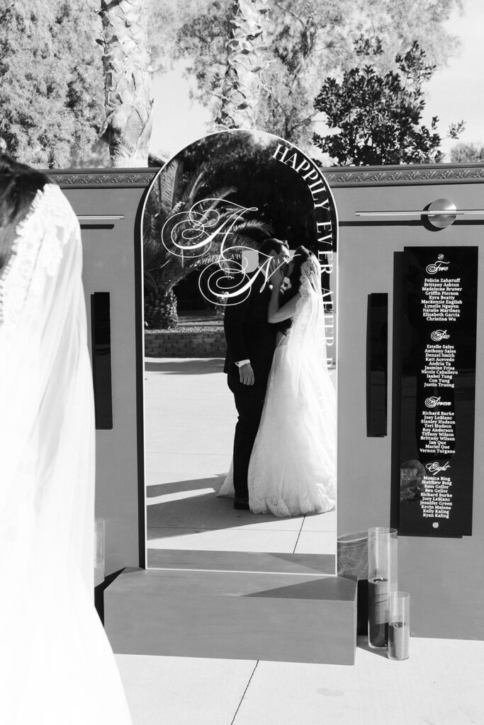 Black and white photo of a couple kissing through the mirror during their cocktail hour.