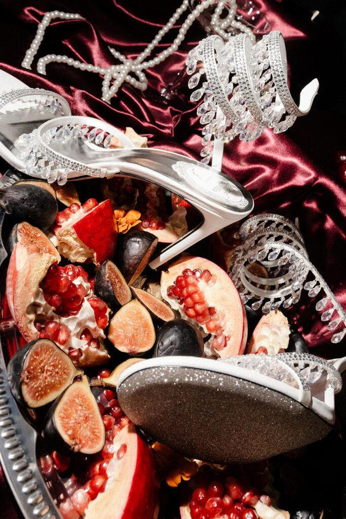 Unique editorial wedding reception detail shot of fruit and heels.