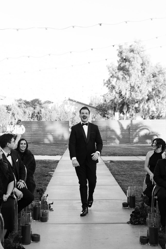 Black and white photo of a groom walking down the aisle for his ceremony at The Lotus House in Las Vegas.