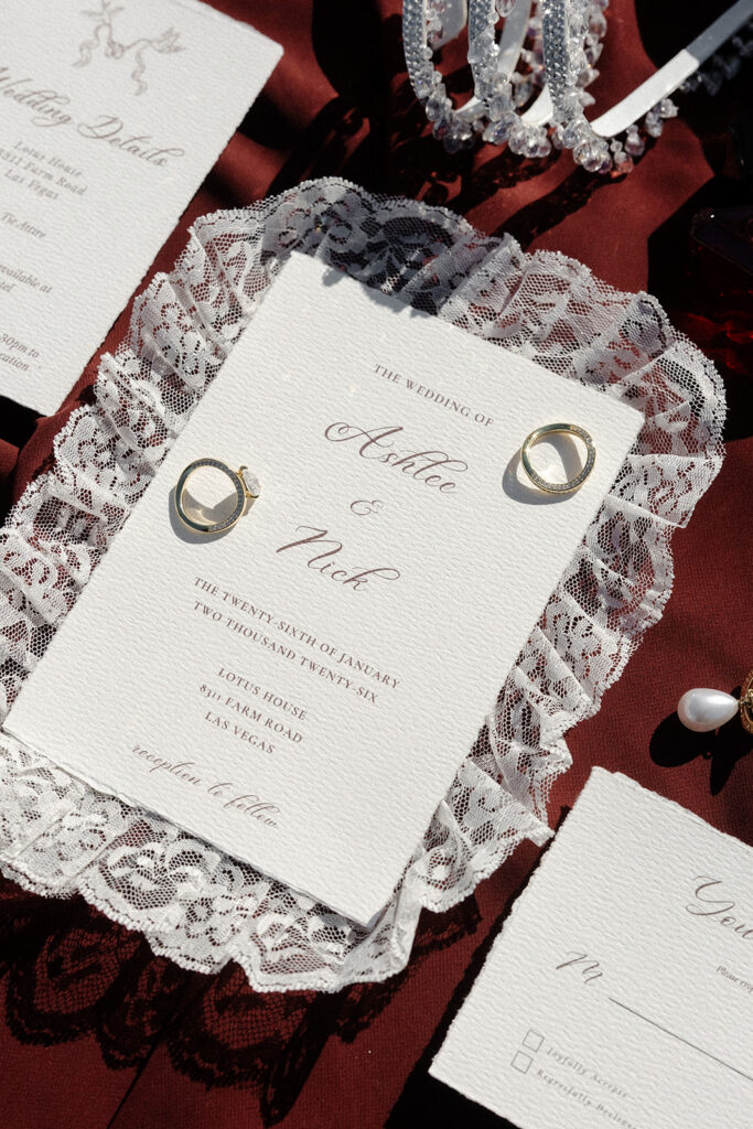 Wedding invitation suite with rings and lace details at The Lotus House wedding venue in Las Vegas.