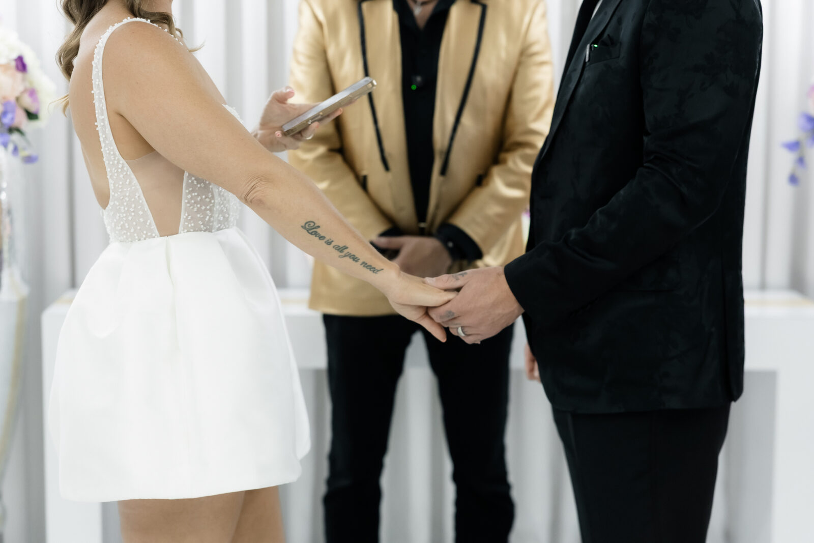Close up photo of a bride and groom holding hands during their Elvis vow renewal at The Little White Wedding Chapel in Las Vegas.