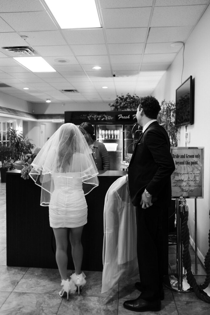Black and white photo of a bride and groom checking in at the desk at A Special Memory Wedding Chapel in Las Vegas.
