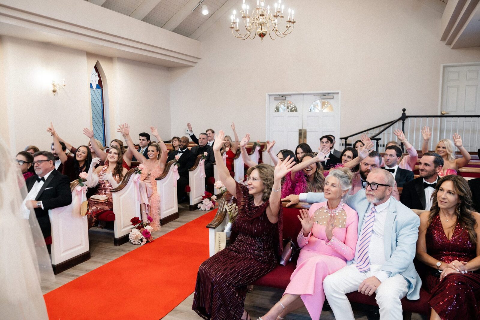 Guests raising their hands in the air during an Elvis wedding ceremony.