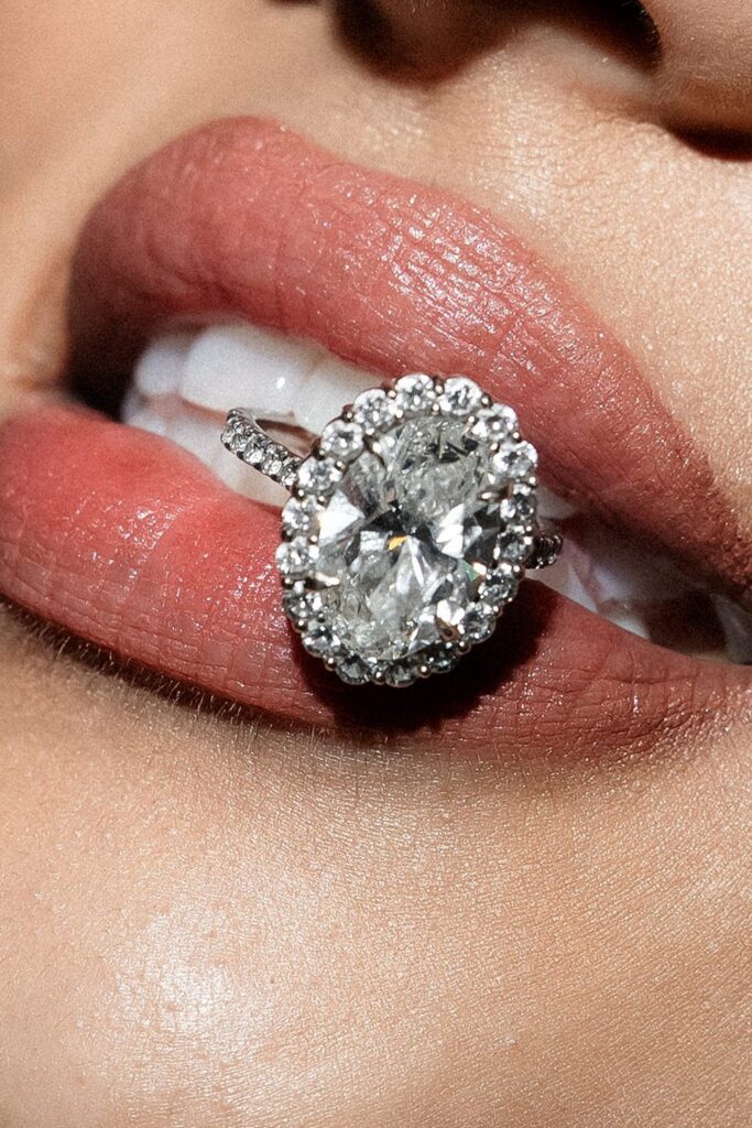 Close up flash photo of a bride holding her wedding ring between her teeth.