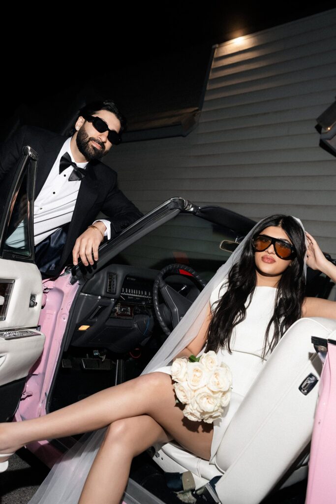 Flash photo of a bride and groom posing with the pink Cadillac outside of A Special Memory Wedding Chapel in Las Vegas.