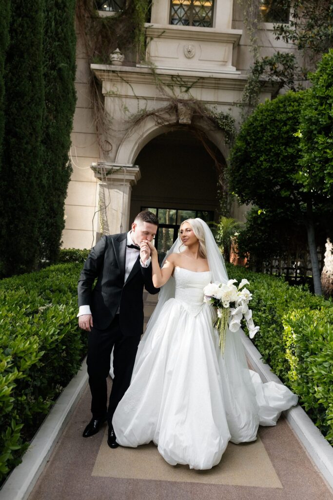 Groom kissing the brides hand as they walk through the gardens at Caesars Palace.