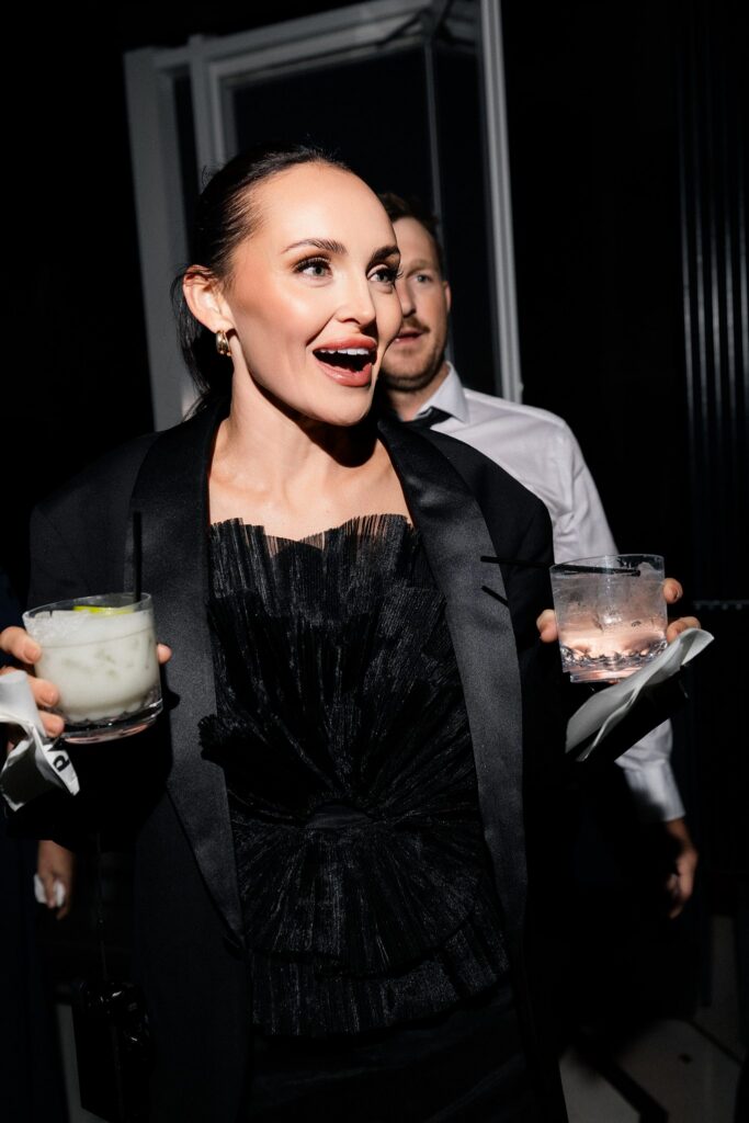 Guest smiling with two drinks in hands during a Las Vegas wedding reception at Ghostbar at The Palms.
