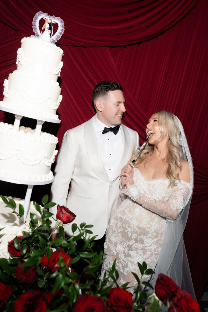 Bride and groom playfully cutting into their wedding cake.