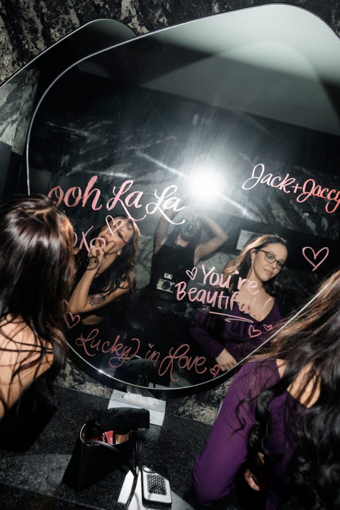Guests writing with lipstick on a mirror during a Las Vegas wedding reception.