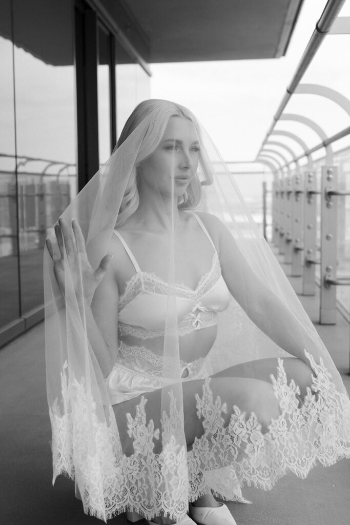 Bride sitting on a balcony in a veil and white getting ready outfit before her Las Vegas wedding.