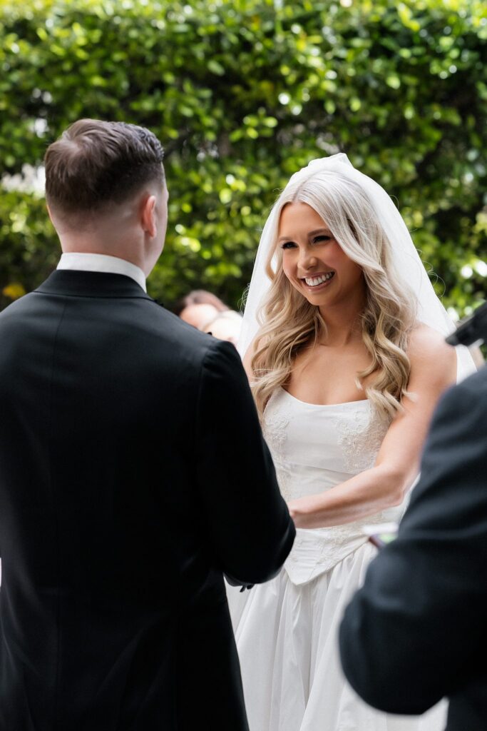 Close up shot of a bride smiling as she holds hands with the groom.