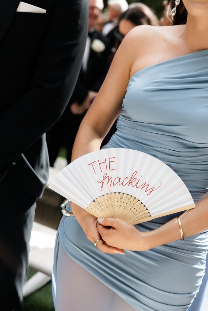 Guest holding a custom fan that says "The Mackins".