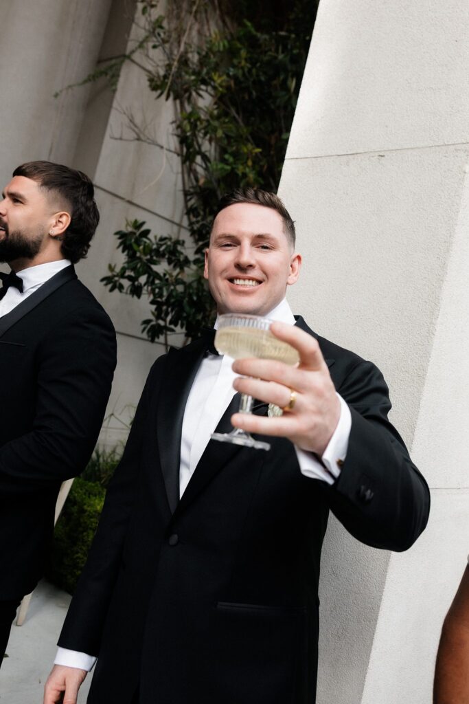 Groom holding a glass of champagne up.