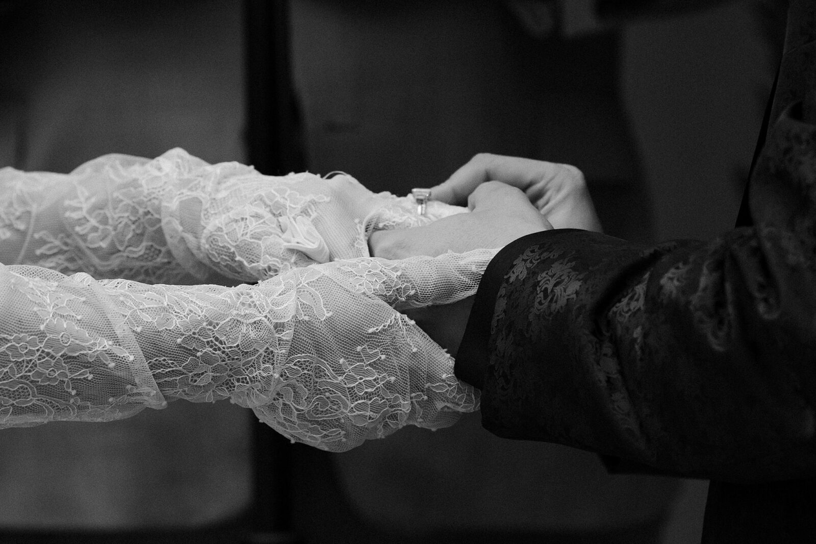 Black and white photo of a bride and groom exchanging rings during their ceremony.