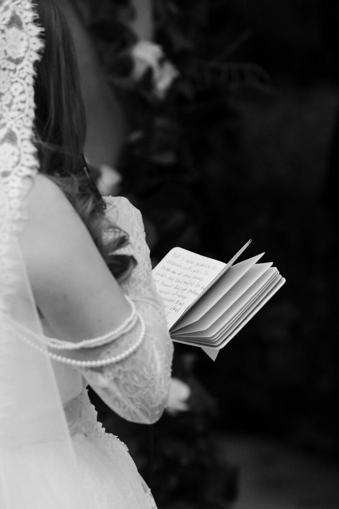 Black and white close up shot of a bride reading her vows.