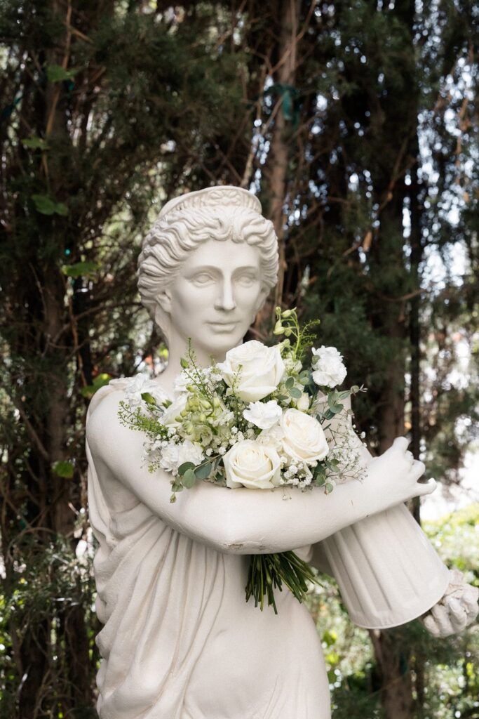 Statue holding the brides white rose wedding bouquet.