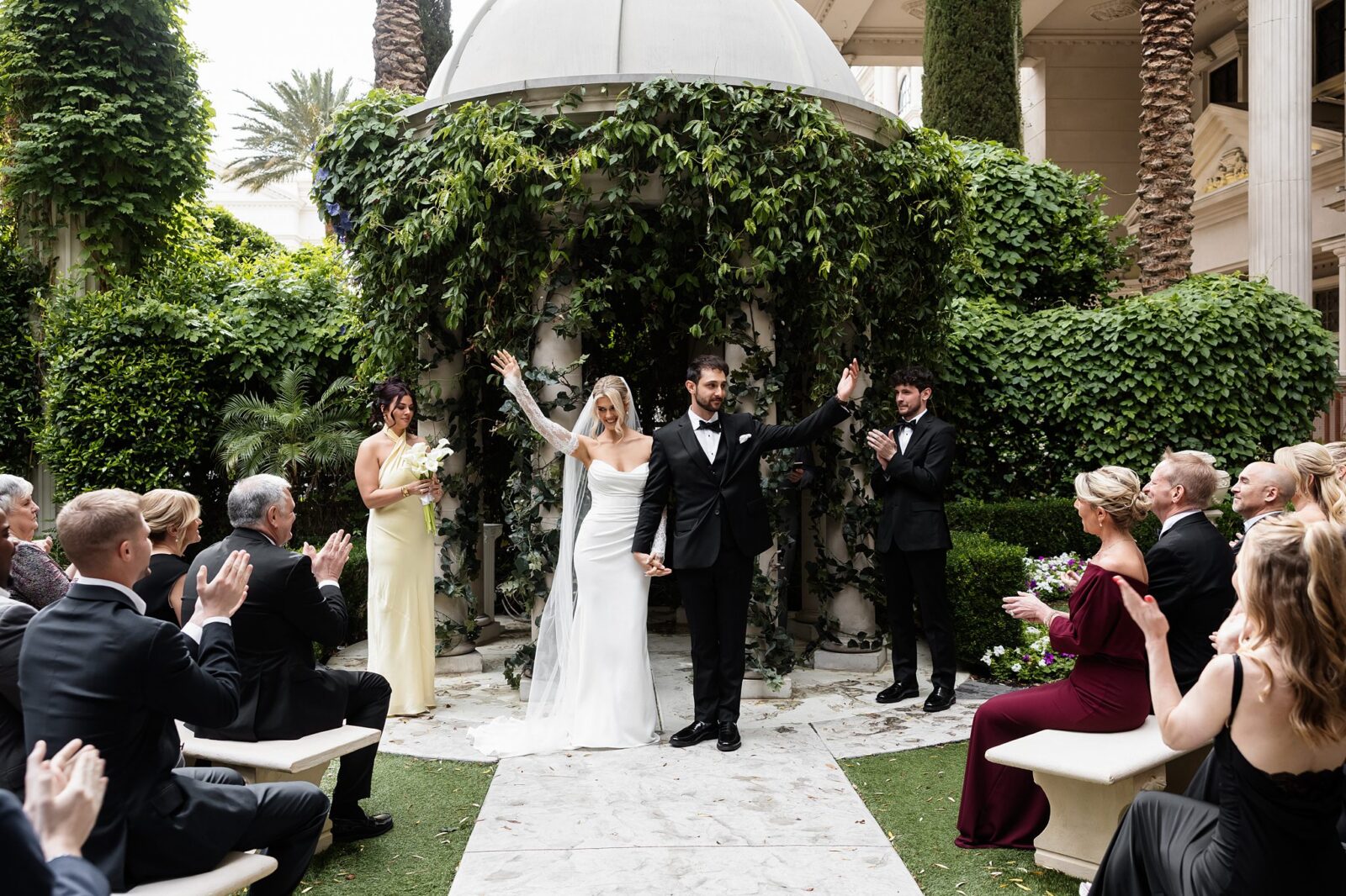Bride and groom raising their hands in the air after their Venus Garden Caesars Palace wedding ceremony.