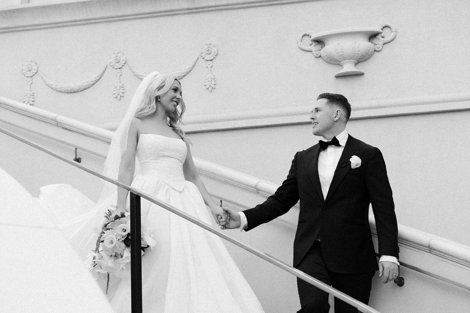 Black and white photo of a bride and groom walking down the stairs at Caesars Palace.