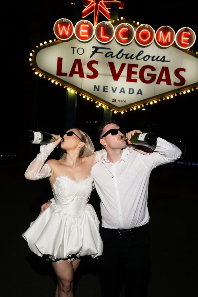 Couple drinking from a bottle of champagne.