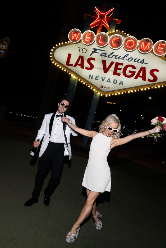 Couple holding hands and walking in front of the sign.