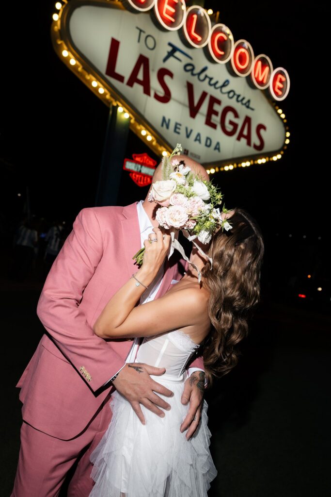 Couple kissing behind the brides wedding bouquet.
