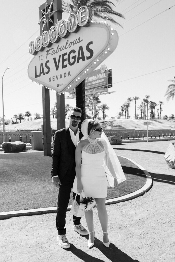 Black and white photo of a couple standing at a side angle for their Welcome to Fabulous Las Vegas sign wedding photos.