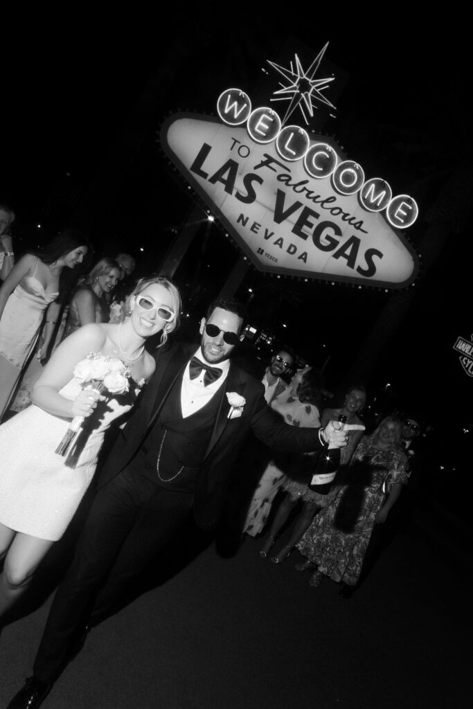 Couple and their guests standing in front of the Welcome to Fabulous Las Vegas sign for their wedding photos.