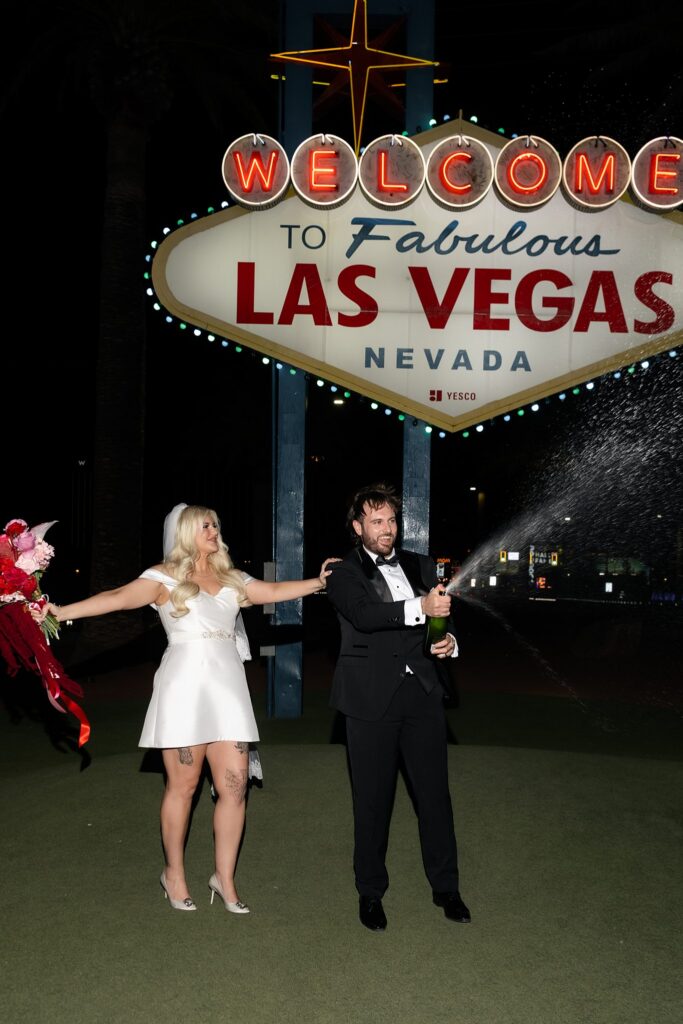 Couple popping a bottle of champagne during their Las Vegas night elopement photos.