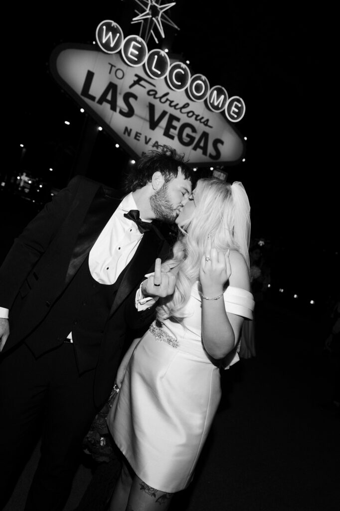 Black and white photo of a couple kissing and showing off their wedding rings.